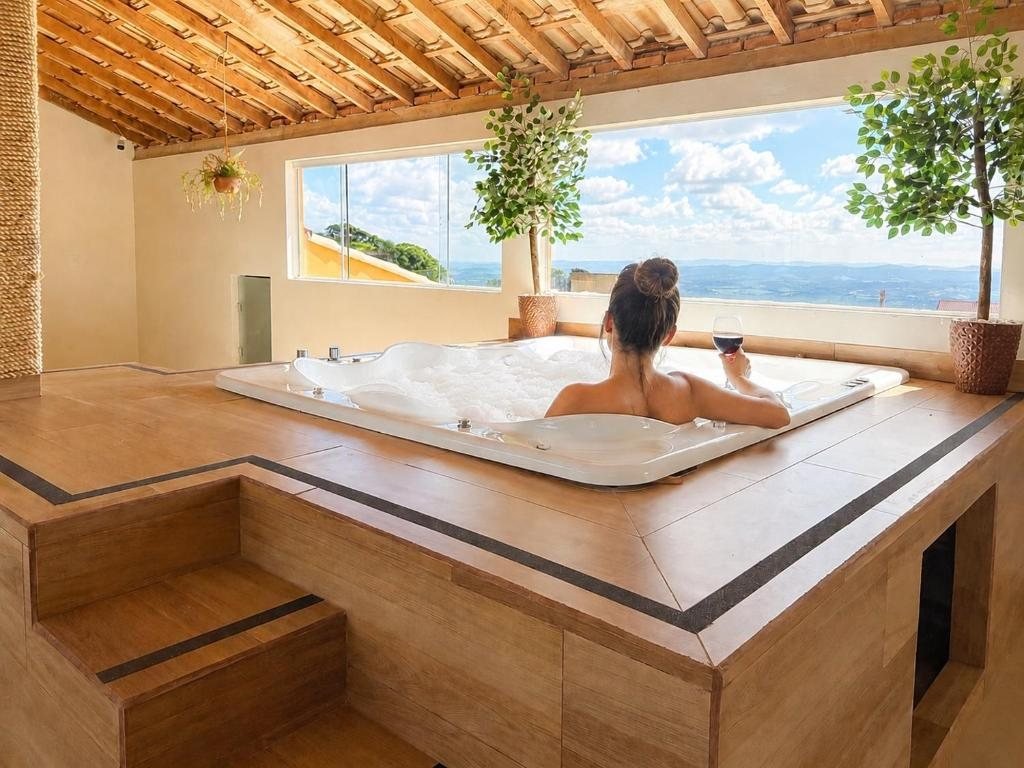 Hóspede na hidromassagem coberta, com a serra vista pelas janelas