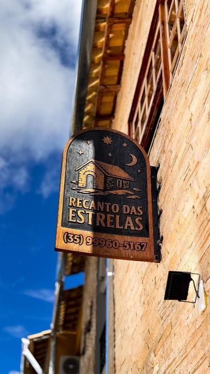 Placa de madeira da Pousada Recanto das Estrelas na parede de pedra